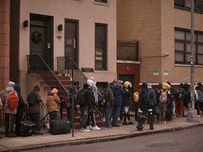 Migrants queue in the cold as they look for a shelter outside a migrant assistance center at St. Brigid Elementary School, Dec. 5, 2023, in New York.