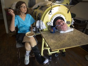 In this April 27, 2018 photo, attorney Paul Alexander chats with caregiver and friend Kathryn Gaines as he drinks coffee and she eats breakfast beside his iron lung at his home in Dallas. Alexander died Monday, March 11, 2024 at a Dallas hospital, said Daniel Spinks, a longtime friend.