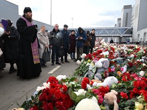 An Orthodox priest leads a service at a makeshift memorial in front of the burnt-out Crocus City Hall concert venue in Krasnogorsk, outside Moscow, on Tuesday, March 26, 2024.