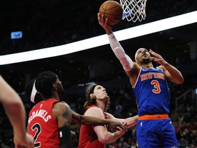 Knicks guard Josh Hart (right) scores as Raptors forwards Jalen McDaniels (left) and Kelly Olynyk (centre) look on during second half NBA action in Toronto, Wednesday, March 27, 2024.