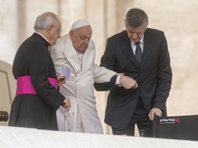 Pope Francis is helped by his aides