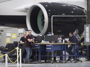 Airbus employees work next to the engine of Airbus A220 at the assembly plant in Mirabel, Que., Thursday, February 20, 2020.