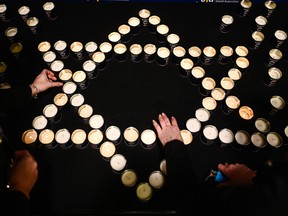 Women light candles in the shape of the Star of David