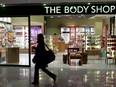 A woman passes a Body Shop cosmetics store