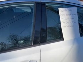 A white car with a note taped to the rear window.