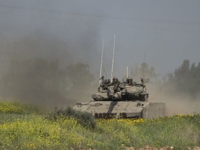 A senior official in Canada's foreign service says Ottawa is still sorting out the implications of the Liberals committing to stop future military exports to Israel. Israeli soldiers move on the top of a tank near the Israeli-Gaza border, as seen from southern Israel, Thursday, March 21, 2024.