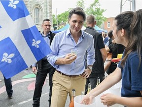 Prime Minister Justin Trudeau talks to a merchant after sampling a cider during an event on Saint-Jean-Baptiste in Montreal, Saturday, June 24, 2023.