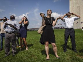 Erika Maynard, centre, watches a solar eclipse from the Washington Monument grounds, on Aug. 21, 2017.