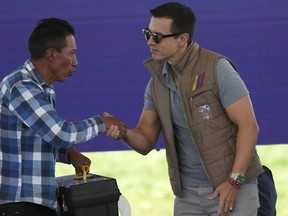 Ecuador's President Daniel Noboa shakes hands with a farmer during his visit to Poalo, Ecuador, Thursday, March 21, 2024, where he met with dairy farmers and handed out 400 land titles.