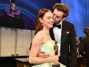 Emma Stone gets a kiss from husband Dave McCary as she holds her Oscar for Best Actress in a Leading Role while attending the 96th Annual Academy Awards at the Dolby Theatre in Hollywood, Calif., on March 10, 2024.