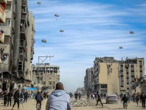 Palestinians run along a street as humanitarian aid is airdropped in Gaza City on March 1, 2024.
