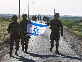 Israeli soldiers walk after coming out from the Gaza Strip, near the border in southern Israel on March 12, 2024, amid the ongoing battles between Israel and the Palestinian militant group Hamas.