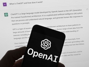 The OpenAI logo is seen on a mobile phone in front of a computer screen which displays output from ChatGPT, March 21, 2023, in Boston.