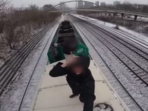 Three people "surfing" on top of GO Transit train.