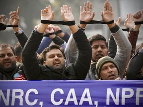 Indians raise their tied hands and shout slogans during a protest against the Citizenship Amendment Act in New Delhi, India, Dec. 27, 2019.