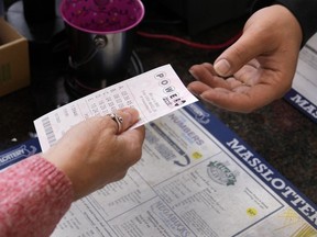 FILE - A customer purchases five Powerball tickets at a lottery agent, Tuesday, Oct. 10, 2023, in Haverhill, Mass.
