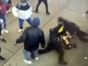 This image taken from video provided by the New York City Police Department shows police officers confronting a group near New York's Times Square, Jan. 27, 2024, bringing a man in a bright yellow coat down to the sidewalk and the chaotic scene that unfolds as at least half a dozen bystanders are seen kicking at the officers, then trying to pry them off the man.