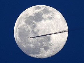 A jet flies northbound as the nearly full moon rises over Washington. MUST CREDIT: Jonathan Newton/The Washington Post.