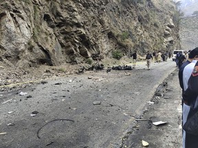 Police officers examine the site of suicide bombing at a highway in Shangla, a district in the Pakistan's Khyber Pakhtunkhwa province, Tuesday, March 26, 2024.