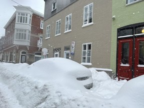 Cars are buried under a heavy layer of snow on a downtown street in Quebec City on January 10, 2024.