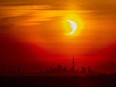 An annular solar eclipse rises over the skyline of Toronto on Thursday, June 10, 2021. A total solar eclipse is a rare celestial event that always generates excitement, but next month's version is expected to be unusually spectacular.