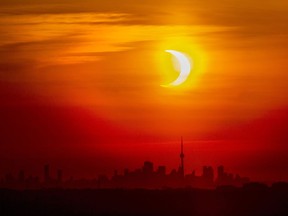 An annular solar eclipse rises over the skyline of Toronto on Thursday, June 10, 2021. A total solar eclipse is a rare celestial event that always generates excitement, but next month's version is expected to be unusually spectacular.