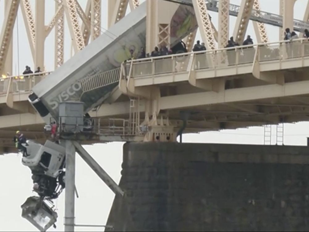 Driver pulled to safety after crash leaves truck dangling over bridge ...