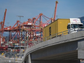 A transport truck carries a cargo container from the Centerm Container Terminal at port in Vancouver, on Friday, July 14, 2023.