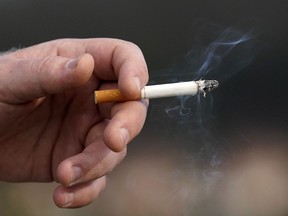 A man holds a lit cigarette