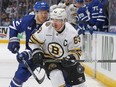 Brad Marchand of the Boston Bruins clears the puck against Jake McCabe of the Toronto Maple Leafs.