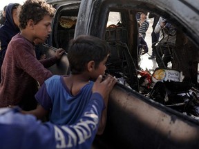 People gather around the carcass of a car used by US-based aid group World Central Kitchen in Deir al-Balah in the central Gaza Strip on April 2, 2024, amid the ongoing battles between Israel and the Palestinian militant group Hamas.