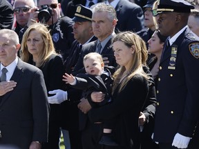 Stephanie Diller, the widow of NYPD officer Jonathan Diller, carries her son Ryan at the funeral of her husband at St. Rose of Lima R.C. Church on March 30, 2024 in Massapequa, N.Y. Officer Diller was killed on March 25 when he was shot in Queens after approaching an illegally parked vehicle. Two suspects have been arrested, charged and are being held and without bail for the murder of Diller.