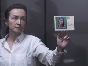 Alsu Kurmasheva, an editor for the U.S. government-funded Radio Free Europe/Radio Liberty's Tatar-Bashkir service, holds a card depicting her portrait and with a sign in Russian that reads" 'They're waiting for her at home', during a court hearing in Kazan, Russia on Monday, April 1, 2024.