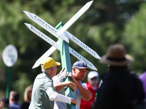 Bryson DeChambeau moves a sign while preparing to play his second shot on the 13th hole from the 14th fairway during the second round of the 2024 Masters Tournament at Augusta National Golf Club in Augusta, Ga., Friday, April 12, 2024.