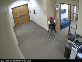 In this screen grab from surveillance video tweeted by the Metropolitan Nashville Police Department, Audrey Elizabeth Hale points an assault-style weapon inside The Covenant School in Nashville, Tenn., Monday, March 27, 2023. The former student shot through the doors of the Christian elementary school and killed several children and adults before being killed by police.