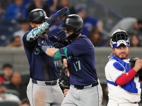 Seattle Mariners' Mitch Haniger celebrates his two-run home run with Julio Rodriguez, left, as Blue Jays catcher Alejandro Kirk looks on during the eighth in Toronto on Tuesday, April 9, 2024.