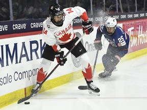 Canada defender Renata Fast (left) looks to pass while pressured by Team U.S.A.'s Alex Carpenter during the first period in the final at the IIHF women's world hockey championship in Utica, N.Y., Sunday, April 14, 2024.