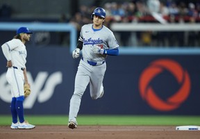 Los Angeles Dodgers designated hitter Shohei Ohtani rounds the bases past Blue Jays shortstop Bo Bichette after hitting a solo home run during first inning in Toronto on Friday, April 26, 2024.
