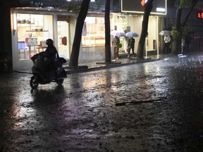 Residents pass through a rain storm in Nanchang in eastern China's Jiangxi province Tuesday, April 2, 2024.