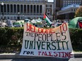 A giant sign is hung over a fence during a protest - Welcome to the people's university for Palestine