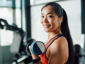 A woman lifts dumbbells during strength training in a gym.