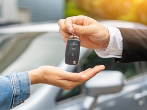 Closeup of two hands, one handing over the set of keys to new vehicle.