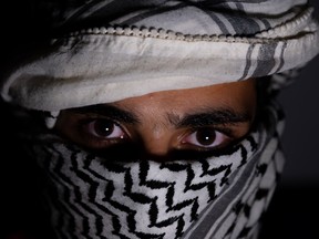 portrait of pearson wearing white keffiyeh on dark background with anger expression on his eyes