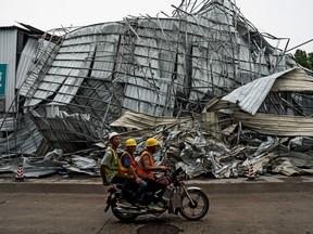 People drive past a damaged building