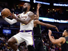 LeBron James #23 of the Los Angeles Lakers goes up for a shot ahead of Herbert Jones #5 and CJ McCollum #3 of the New Orleans Pelicans at Smoothie King Center on April 14, 2024 in New Orleans, La.