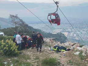 Rescue and emergency team members work with passengers of a cable car transportation system outside Antalya, southern Turkey, Friday, April 12, 2024.