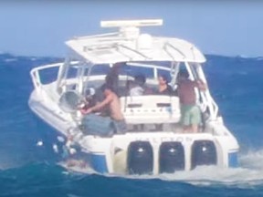 Screenshot of two guys emptying garbage cans into ocean from boat.