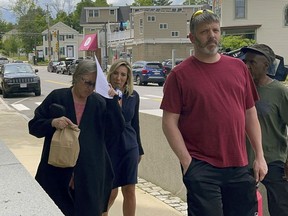 Denise Lodge, left, covers her face with a printout of the indictment against her as she walks from the federal courthouse, Wednesday, June 14, 2023, in Concord, N.H., following her arrest on charges related to an alleged scheme to steal and sell donated body parts.
