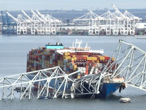 steel frame of the Francis Scott Key Bridge sits on top of a container ship