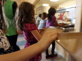 Children line up for food to be served at a school cafeteria.